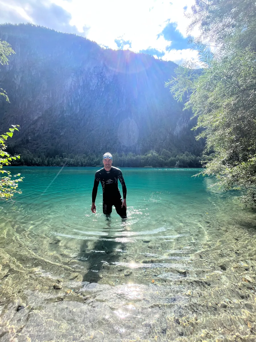 Ein Schwimmer steht im klaren Wasser eines Baches, umgeben von Bäumen